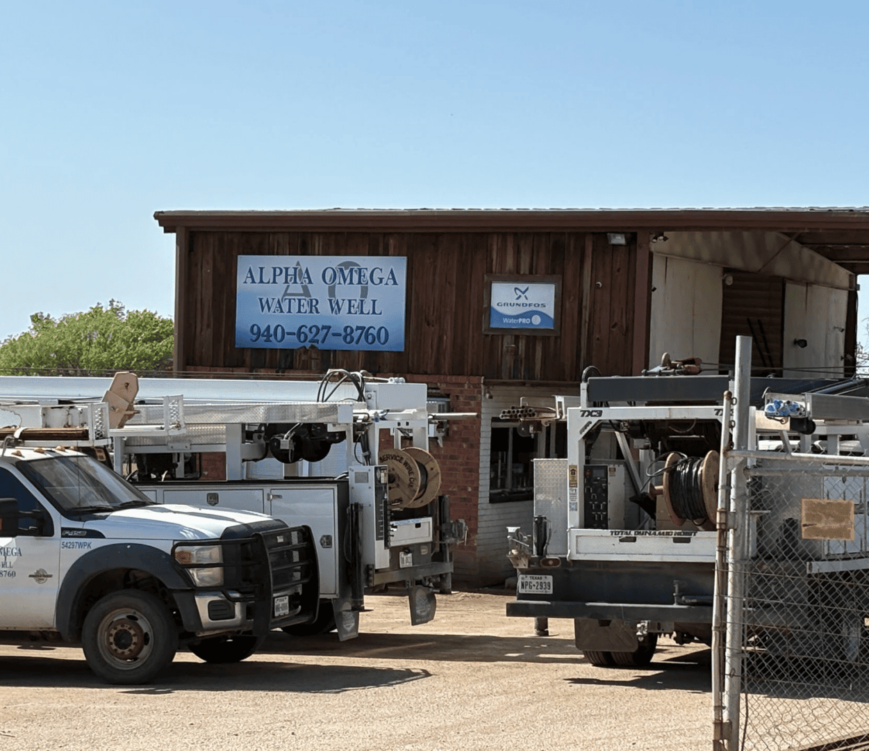 Water well service trucks parked outside building.